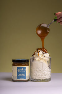 Image of 6 oz jar of fleur de sel caramel sauce made by Jonboy Caramel next to a delicuous cup of vanilla ice cream with Jonboy caramel hand drizzled on top